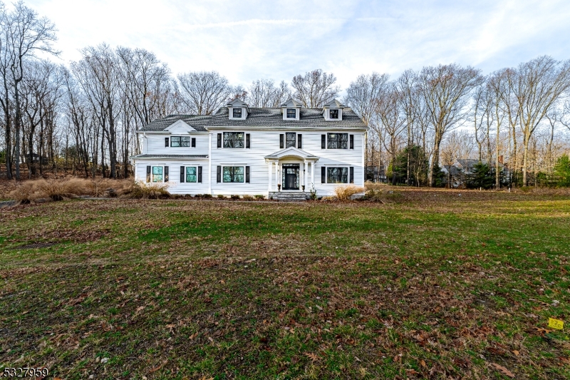 a front view of a house with a garden and trees