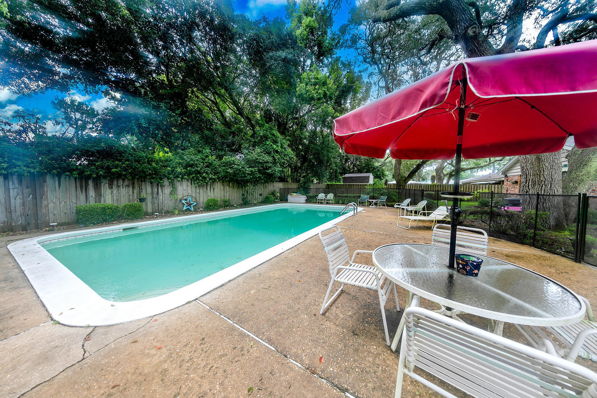 a view of a swimming pool with red chairs under an umbrella