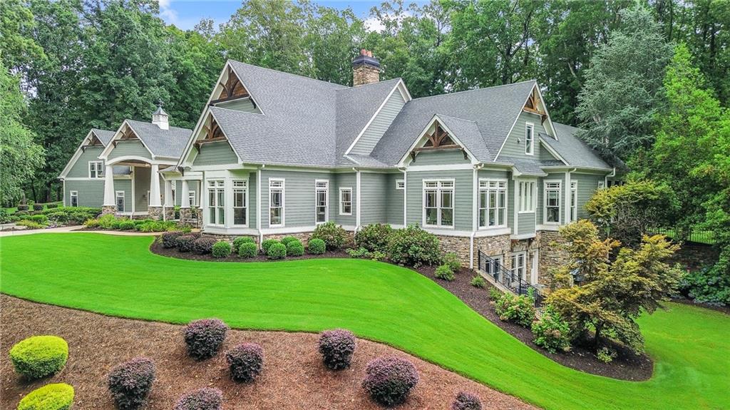 a view of a house with a big yard potted plants and large tree