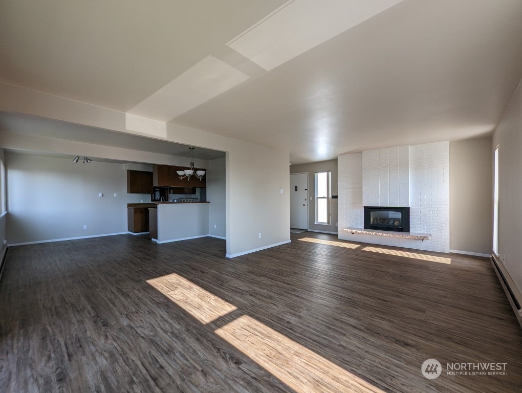 a view of empty room with wooden floor and kitchen