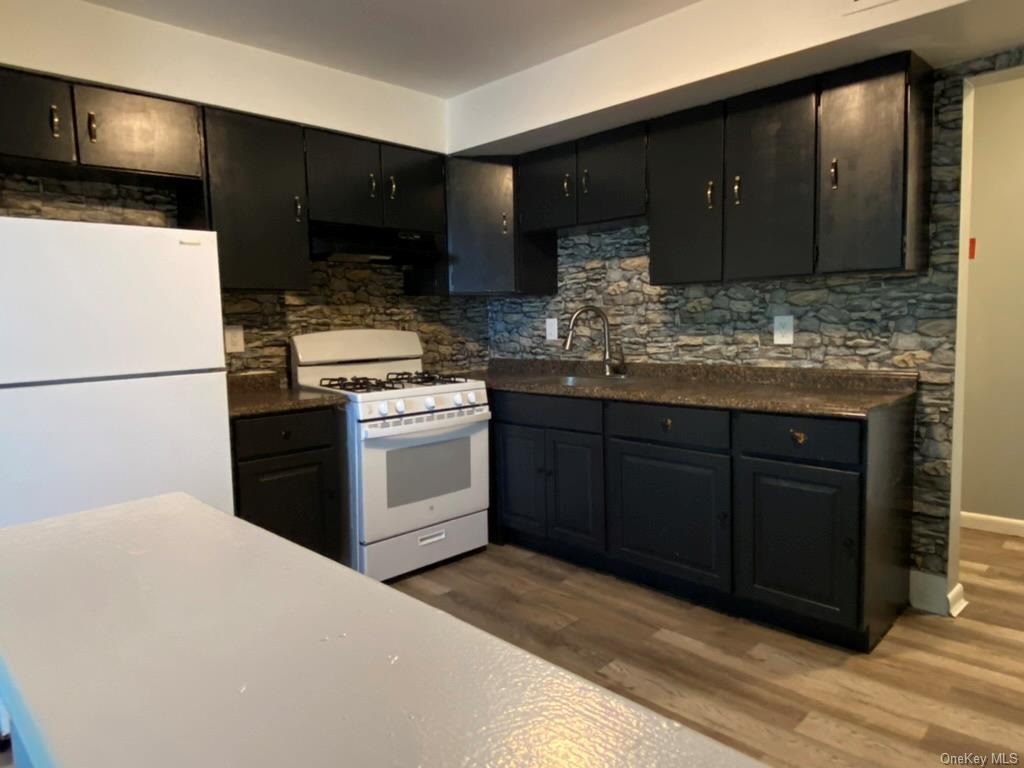 Kitchen with backsplash, white appliances, sink, and dark hardwood / wood-style flooring