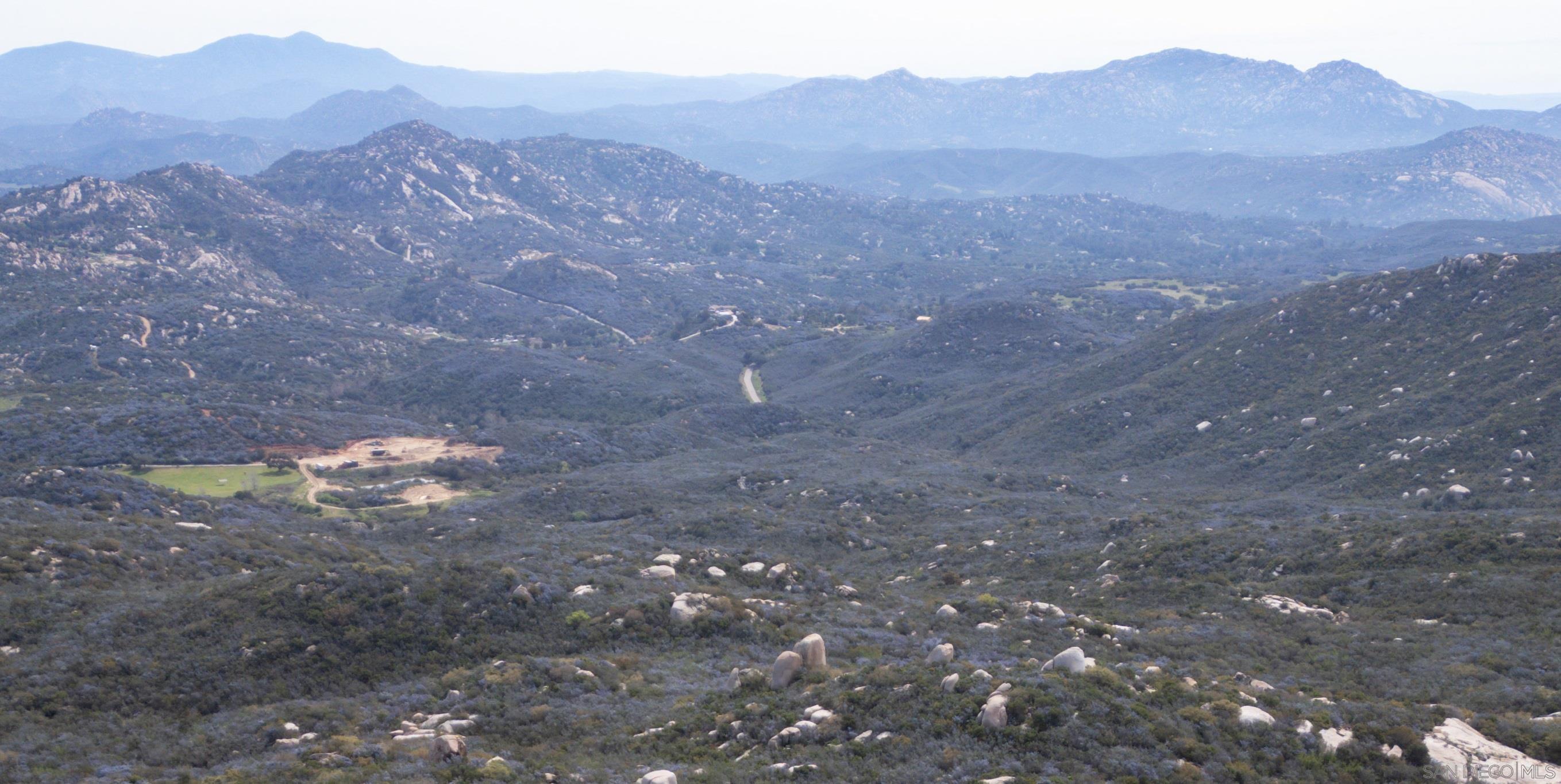 a view of a dry yard with mountains in the background