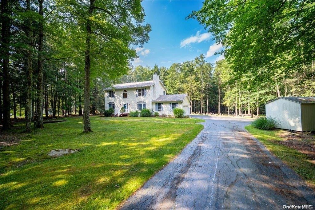 a front view of a house with garden and trees