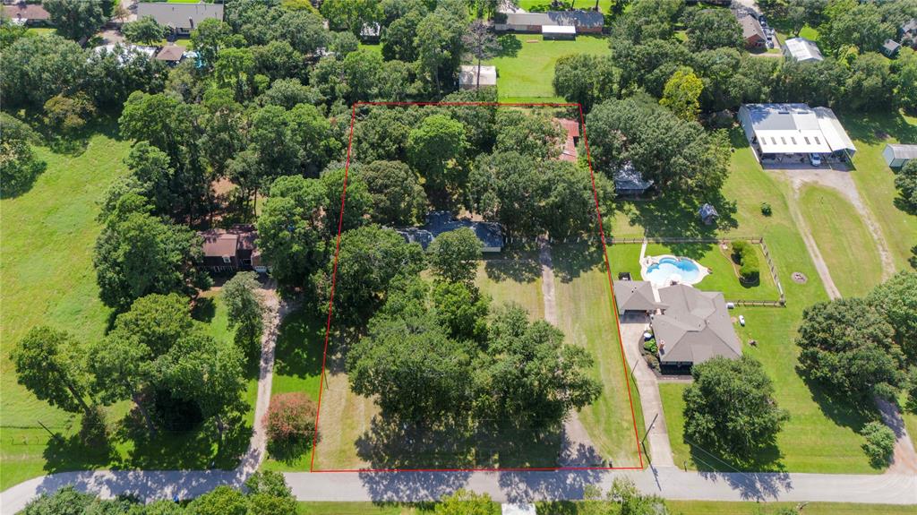 an aerial view of residential house with outdoor space and trees all around