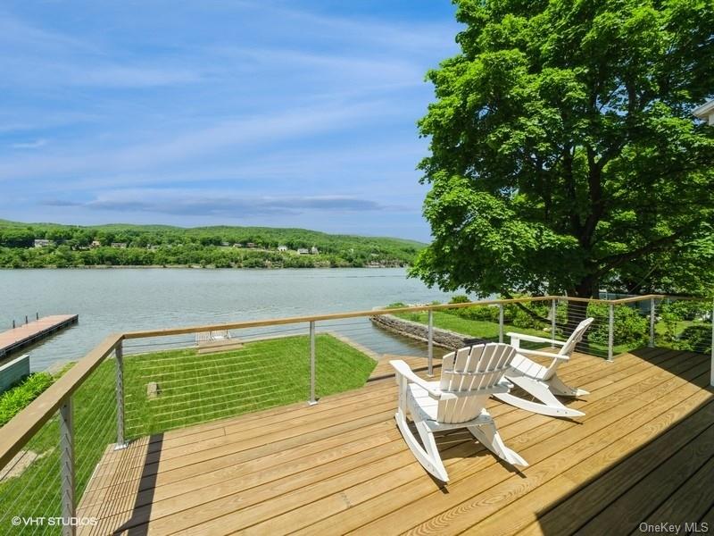 a view of a chairs and table on wooden deck with lake view