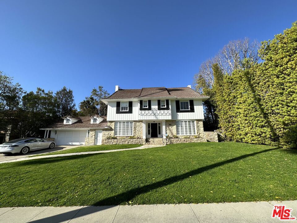 a front view of a house with a garden and trees