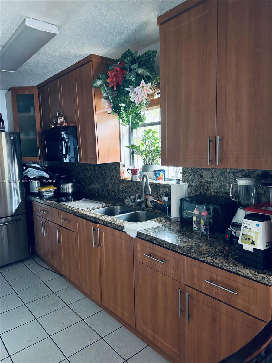 a kitchen with granite countertop cabinets sink and refrigerator