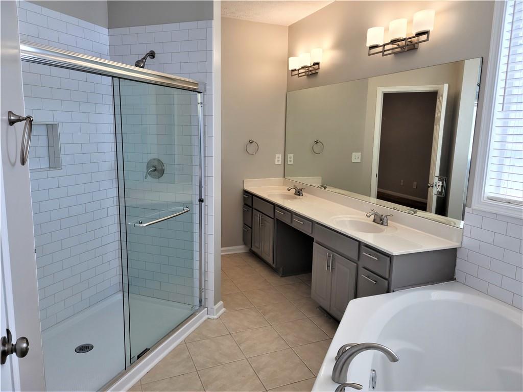 a bathroom with a tub sink shower and mirror