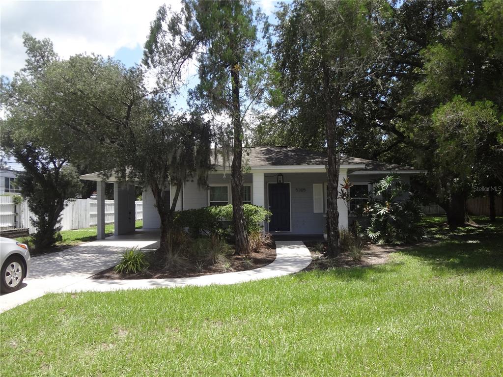 a front view of a house with garden and tree