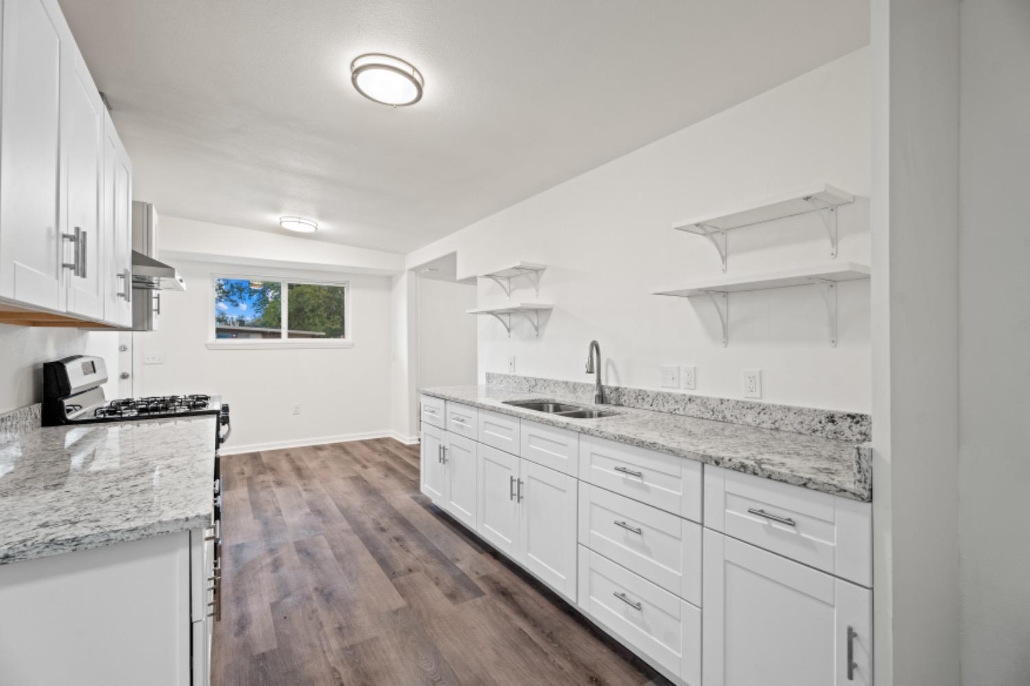 a kitchen with granite countertop a sink cabinets and wooden floor