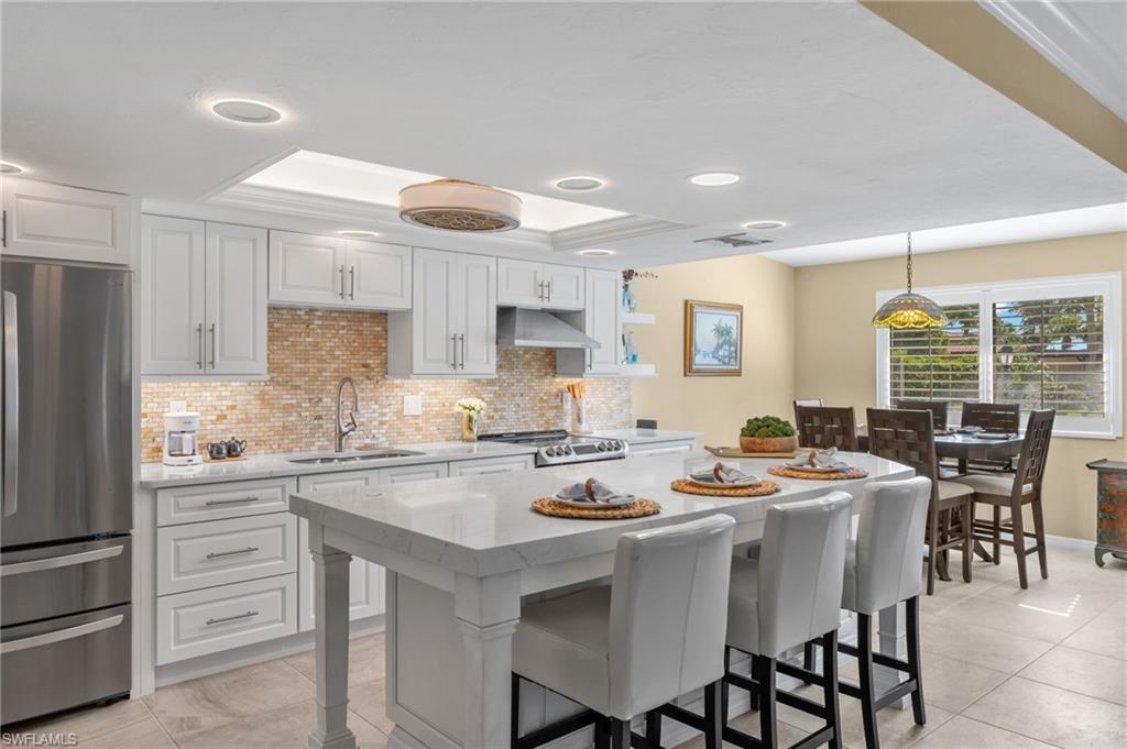 a kitchen with stainless steel appliances kitchen island granite countertop a table chairs stove and cabinets