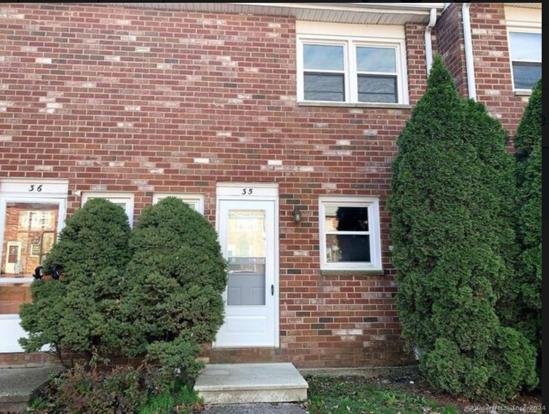 a brick building with a yard and potted plants