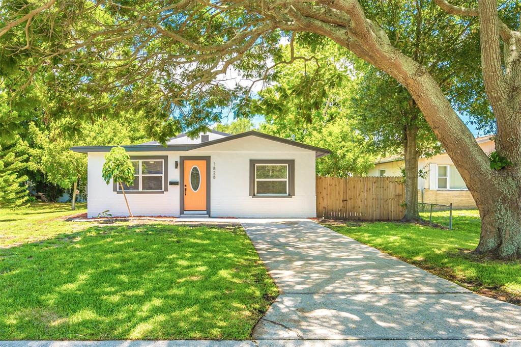 a view of a house with a yard and large tree