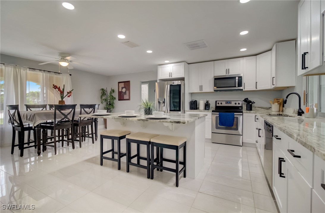 a kitchen with kitchen island granite countertop a stove a sink a dining table and chairs