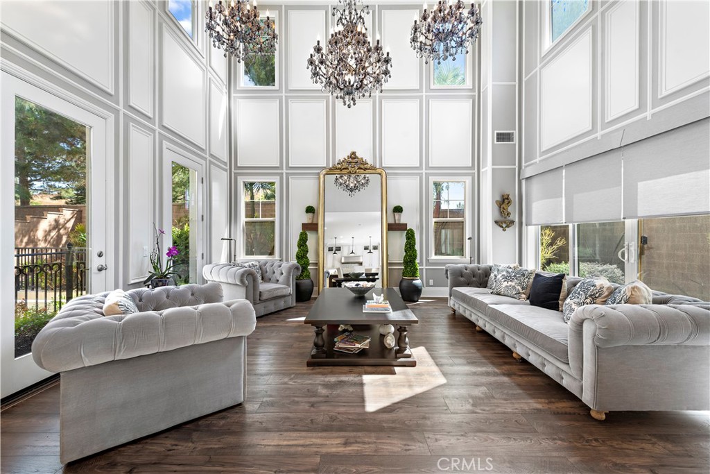 a living room with furniture large windows and wooden floor