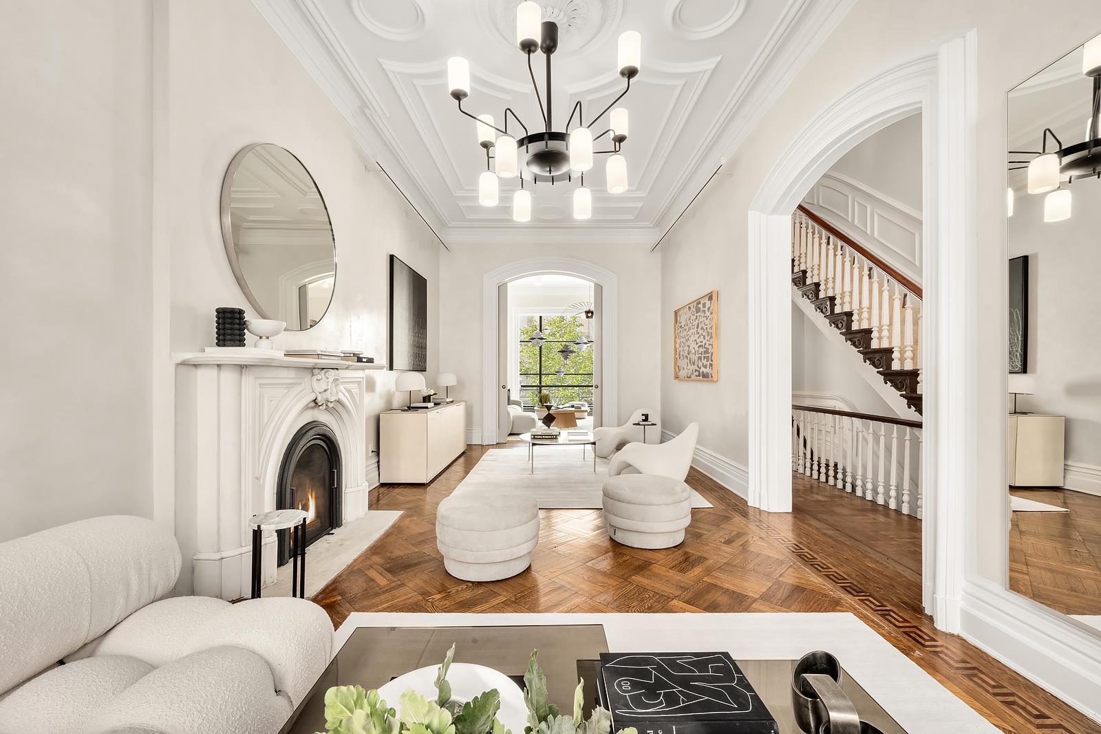 a living room with fireplace chandelier and open kitchen view