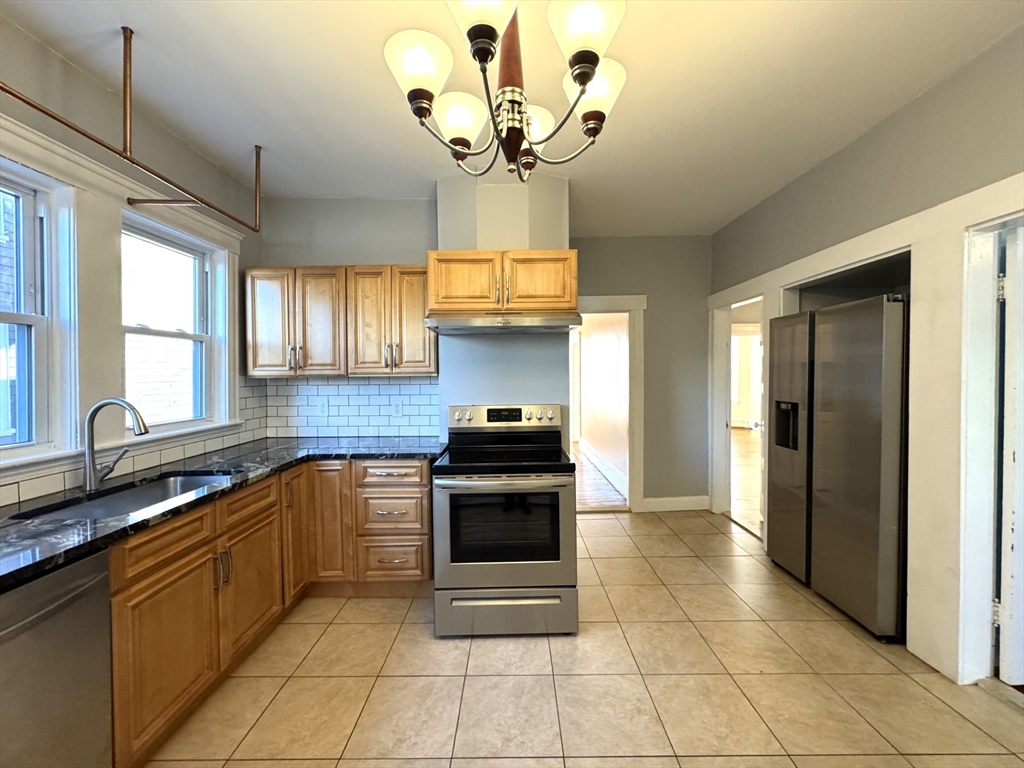 a kitchen with stainless steel appliances granite countertop a stove a sink and a refrigerator