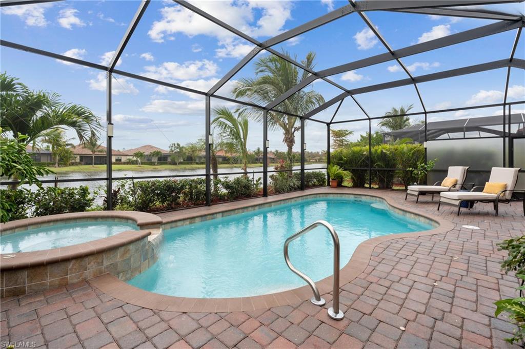 View of swimming pool with a patio area, an in ground hot tub, a water view, and glass enclosure