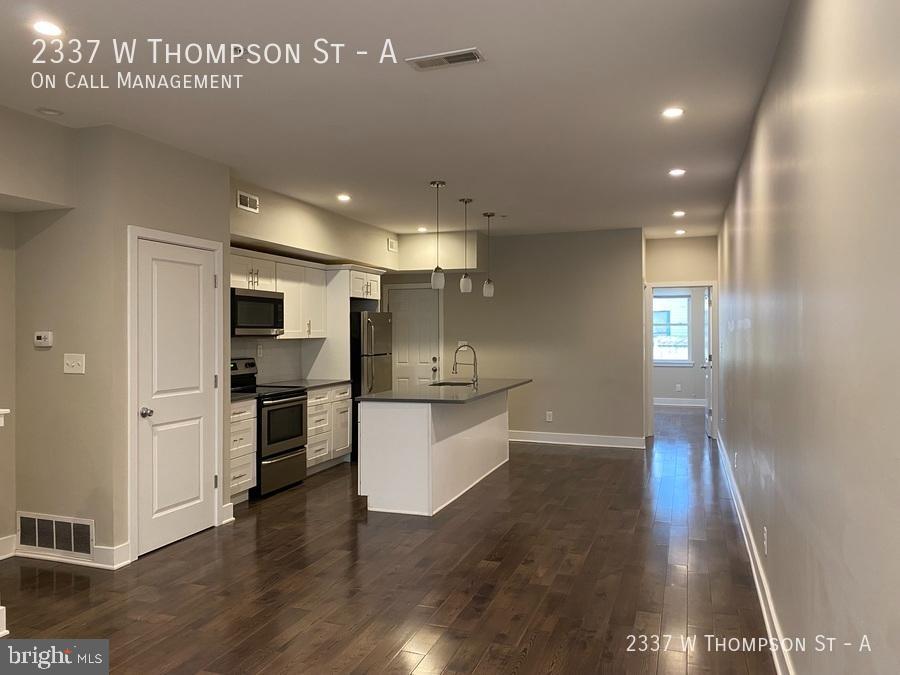 a kitchen with stainless steel appliances a refrigerator and wooden floor