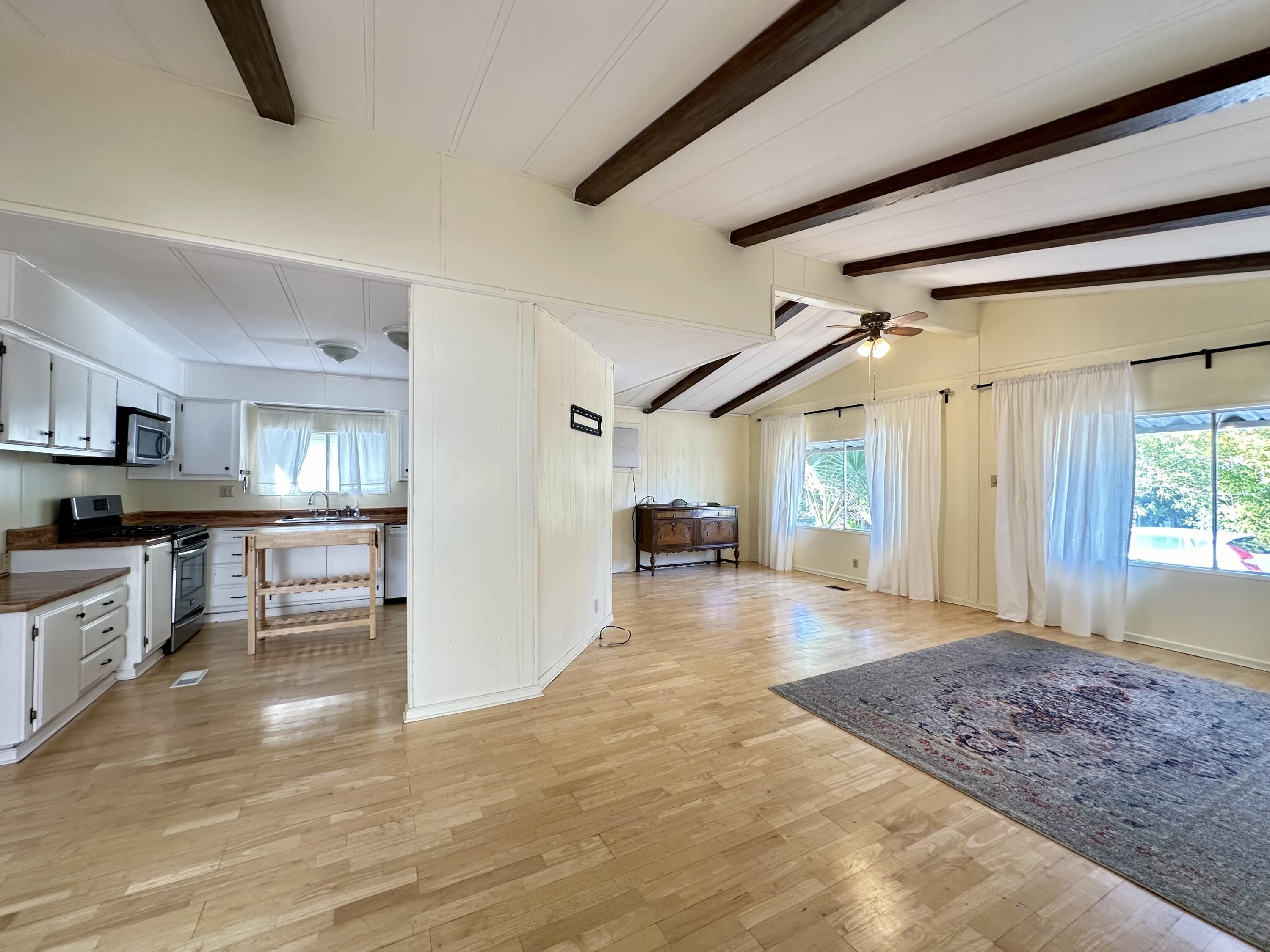 a view of a big room with wooden floor and a kitchen