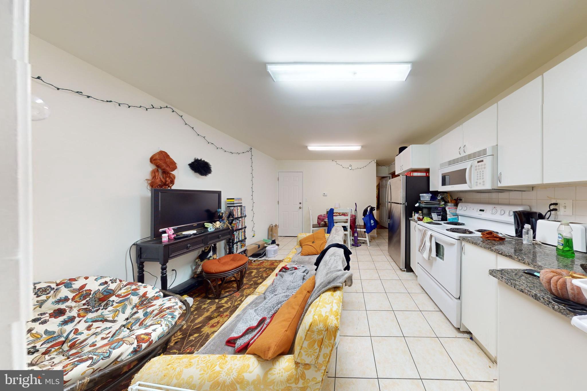 a very nice looking living room with stainless steel appliances furniture a rug and a kitchen view