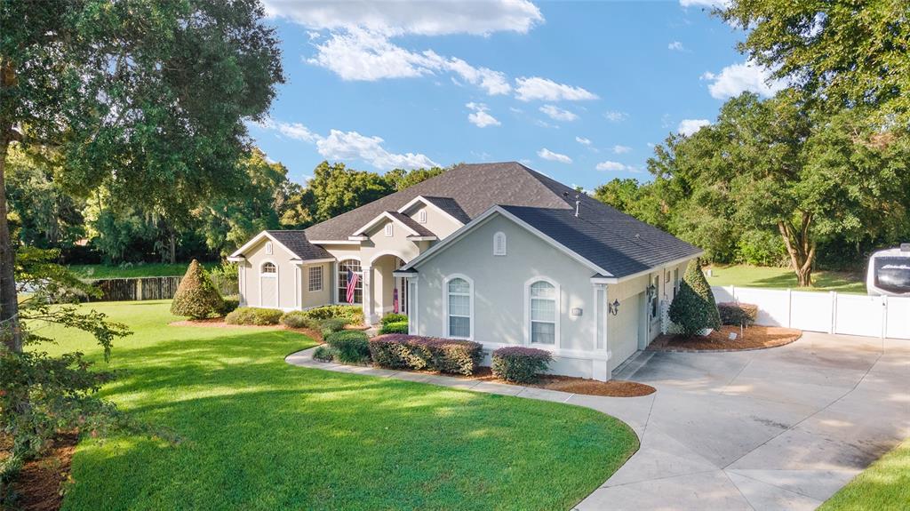 a view of a house with a big yard plants and large trees