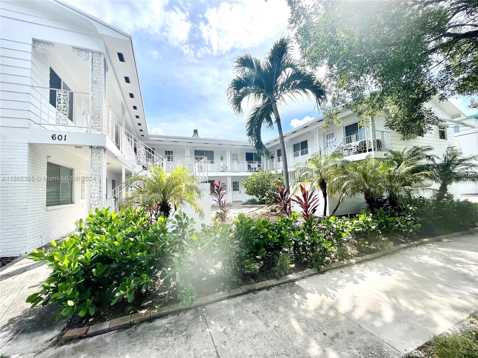 a front view of a multi story residential apartment building with yard and green space