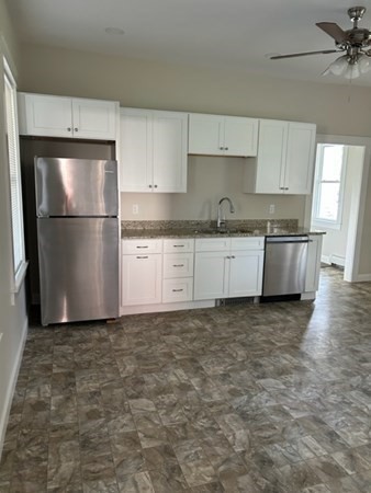 a kitchen with granite countertop a refrigerator and a sink