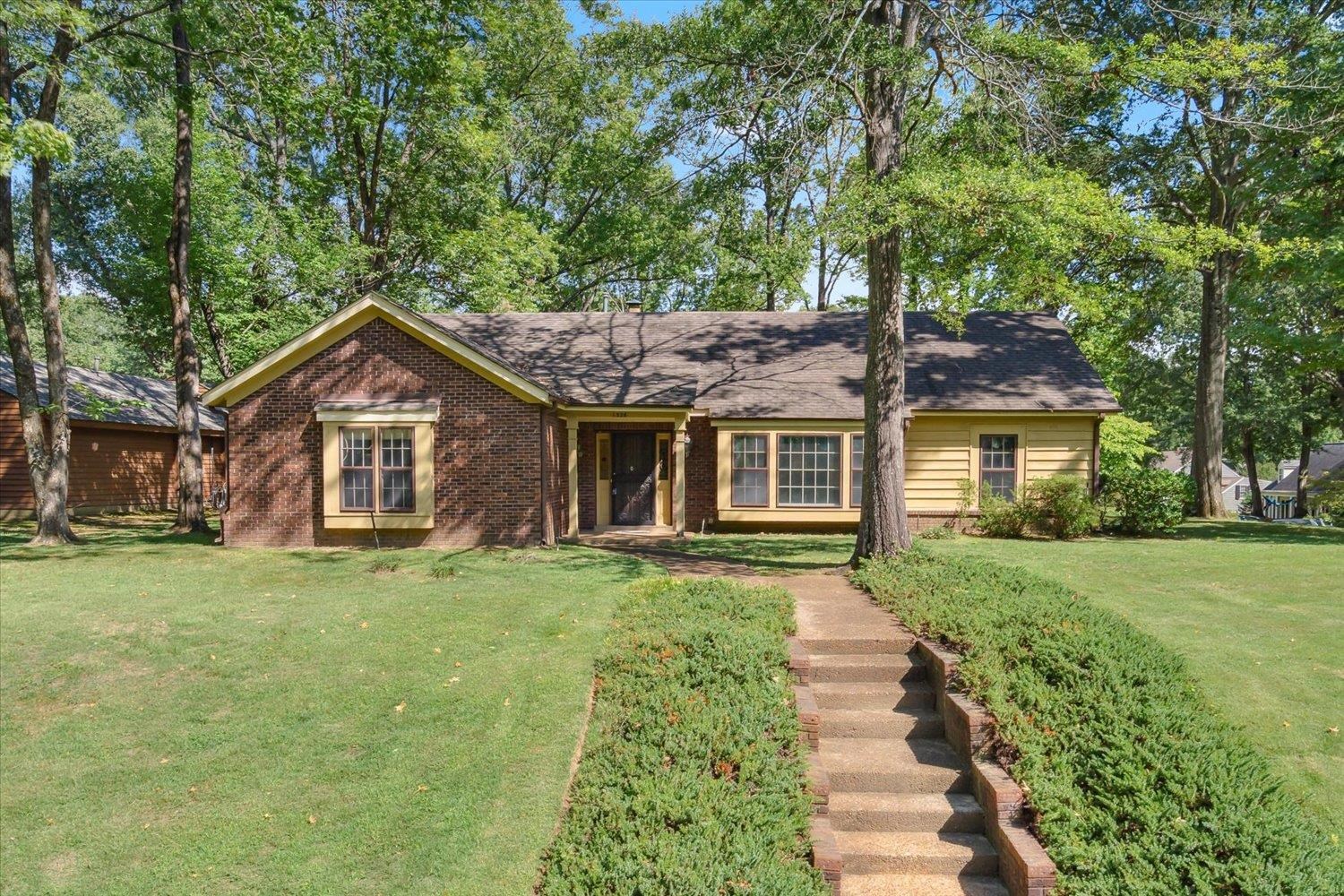 a front view of a house with a yard and trees