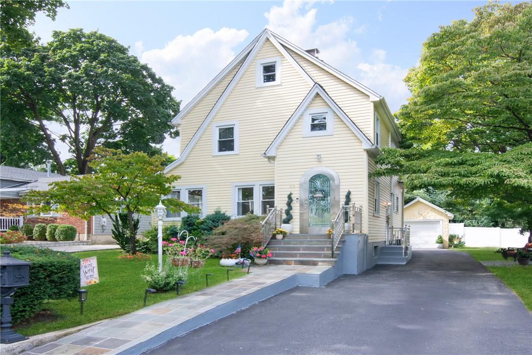 View of front of house with a garage, a front lawn, and an outbuilding