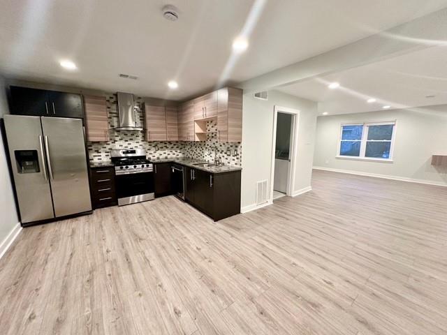 a kitchen with stainless steel appliances kitchen island granite countertop a refrigerator and a sink