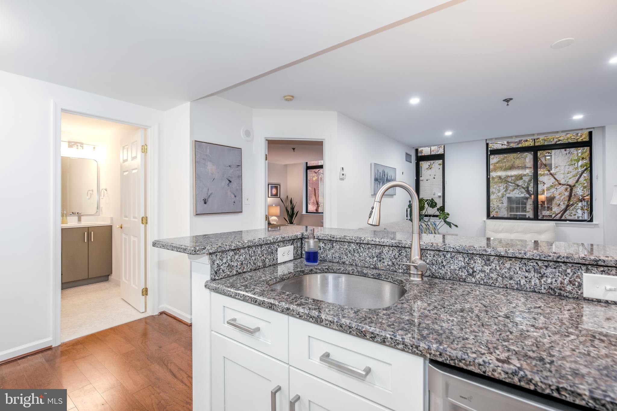 a kitchen with granite countertop a sink and a white wooden cabinets