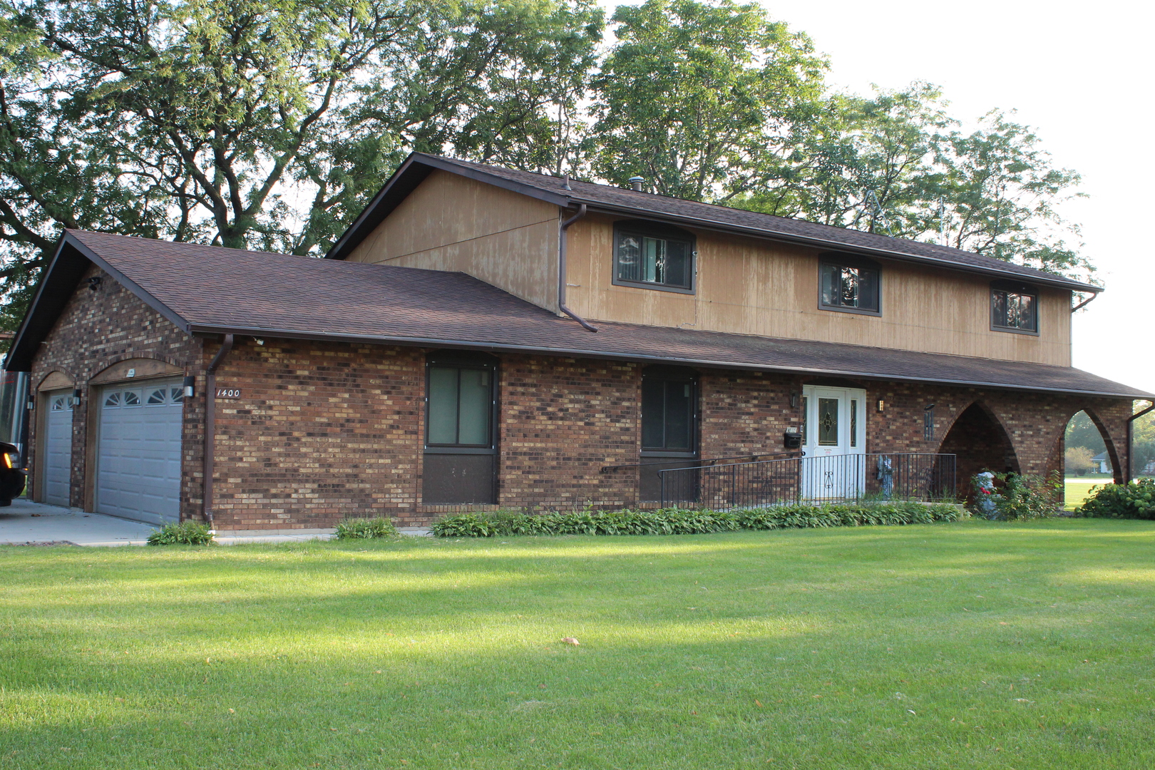 a brick house with a big yard and large trees