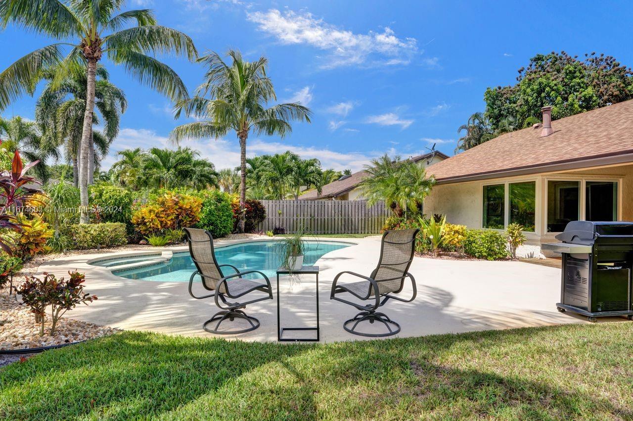 a view of a backyard with table and chairs potted plants and palm tree