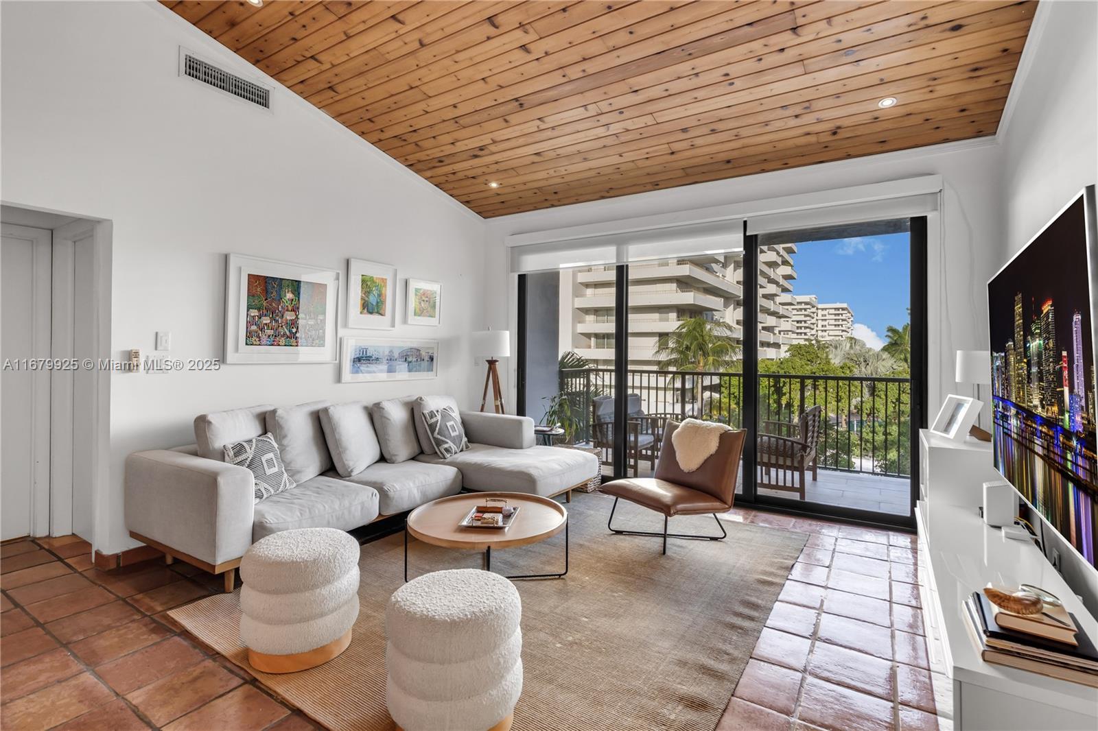 a living room with furniture floor to ceiling window and a flat screen tv