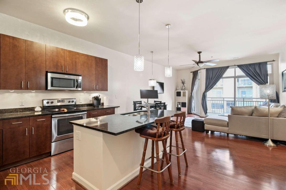 a kitchen with stainless steel appliances granite countertop wooden floors a stove and a center island