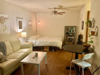 a bedroom with a bed a couch and a dresser with wooden floor