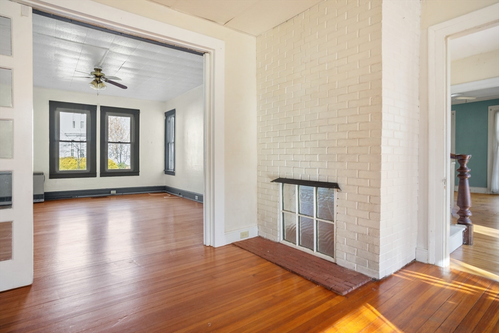 a view of a livingroom with wooden floor and a kitchen