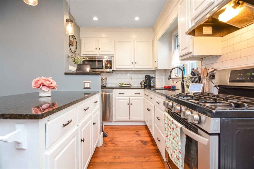 a kitchen with granite countertop a stove top oven a sink dishwasher and cabinets with wooden floor