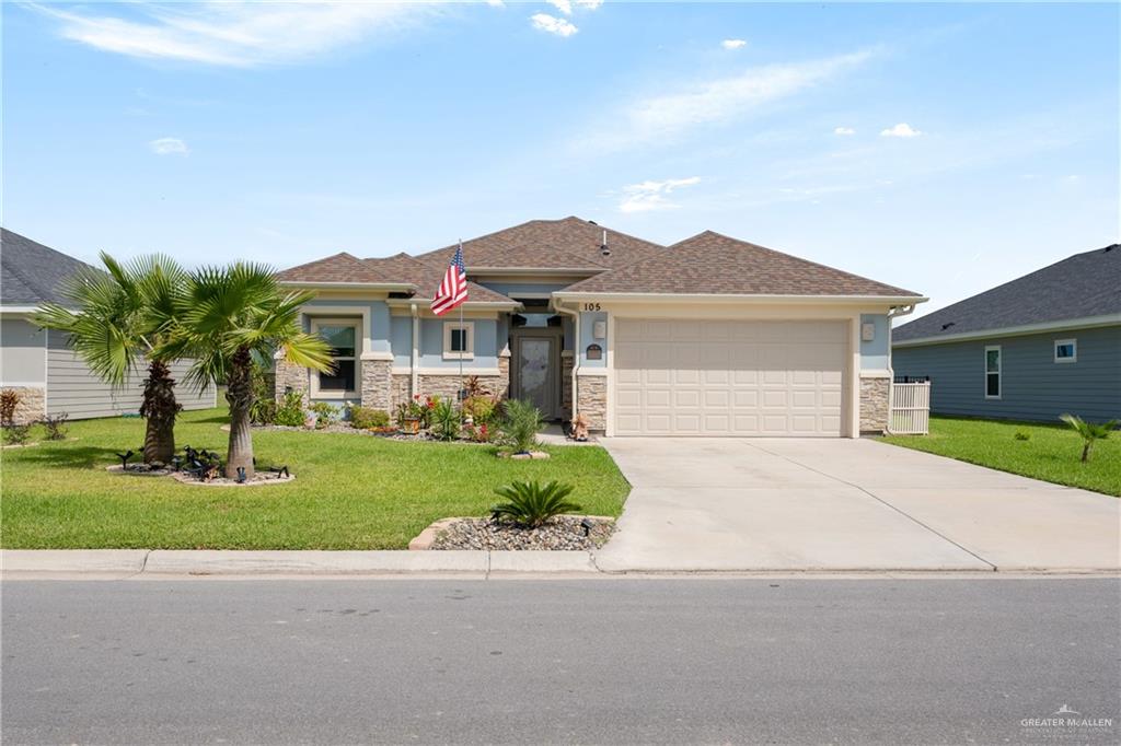 View of front of property with a garage and a front lawn