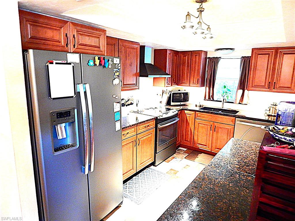 a kitchen with stainless steel appliances granite countertop a refrigerator a sink dishwasher and wooden cabinets