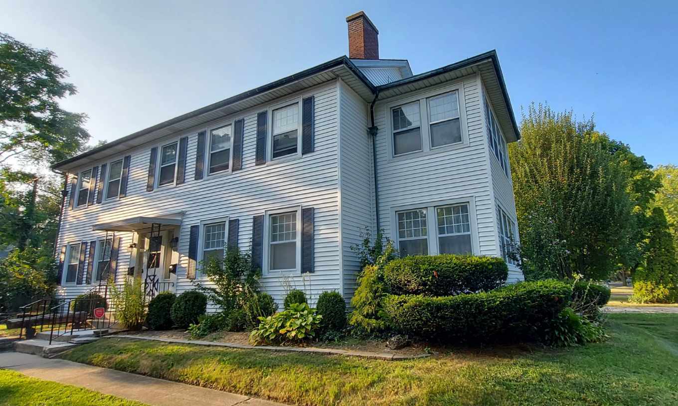 a front view of a house with a yard and potted plants