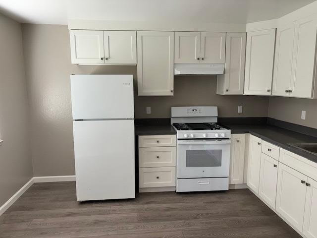 a kitchen with cabinets appliances and a wooden floor