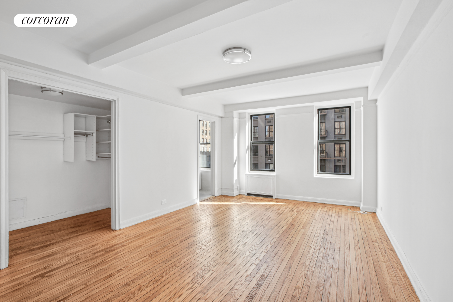 a view of an empty room with wooden floor and a window