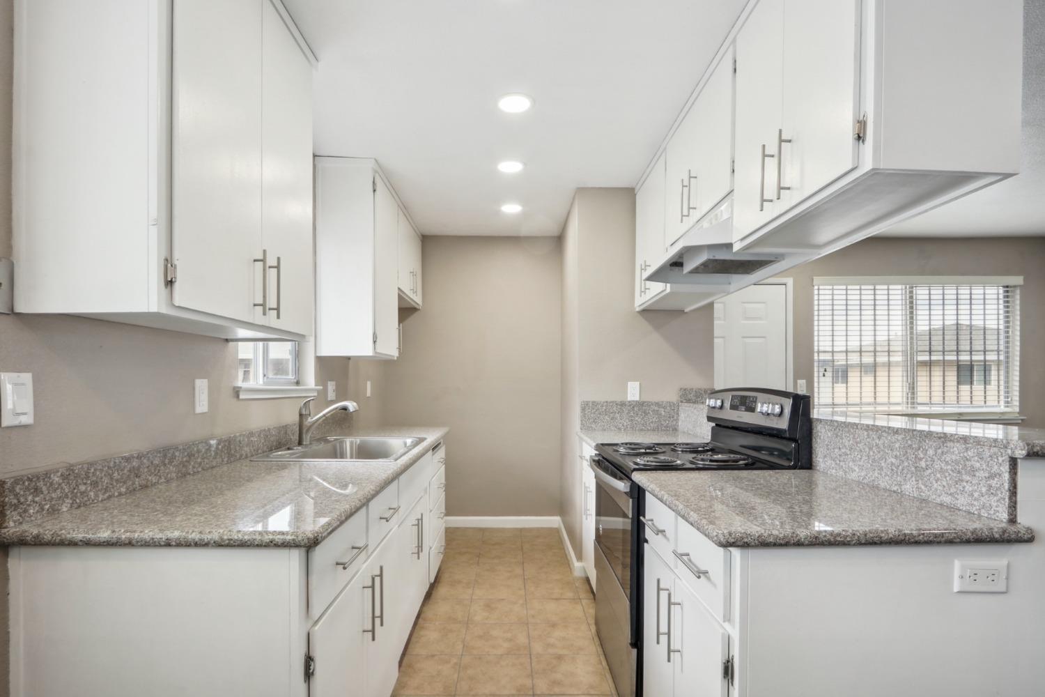 a kitchen with granite countertop a sink a stove and a granite counter tops