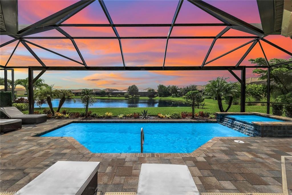 Pool at dusk with a patio, a water view, a lanai, and an in ground hot tub