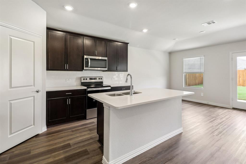 a kitchen with stainless steel appliances kitchen island granite countertop a stove and a refrigerator