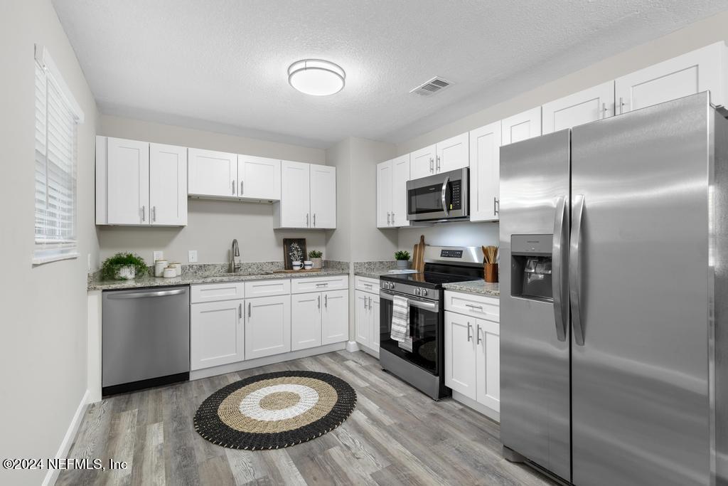 a kitchen with granite countertop a sink stove and refrigerator