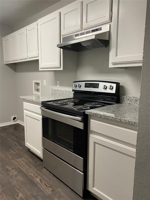 a kitchen with stainless steel appliances granite countertop a stove a microwave and a white cabinets