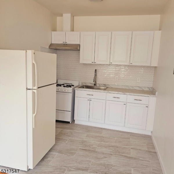 a kitchen with stainless steel appliances granite countertop a refrigerator sink and white cabinets